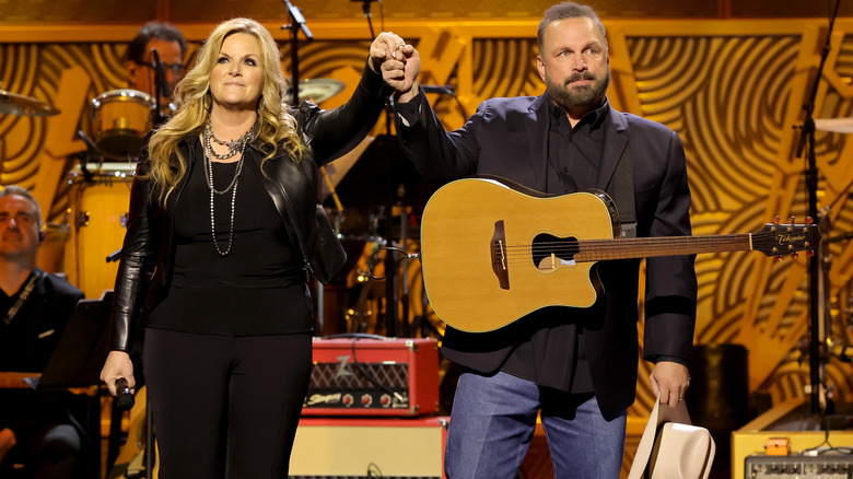 Garth Brooks and Trisha Yearwood holding hands on stage