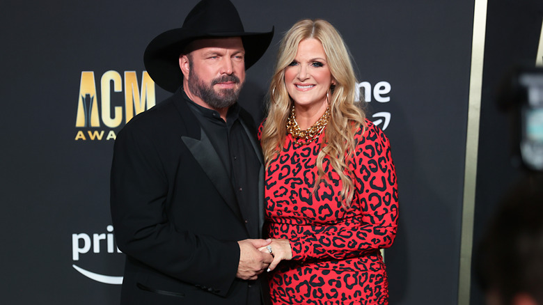 Garth Brooks and Trisha Yearwood holding hands as they pose for a photograph