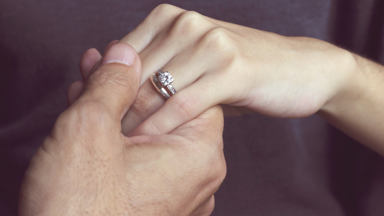 Man holding woman's hand engagement ring