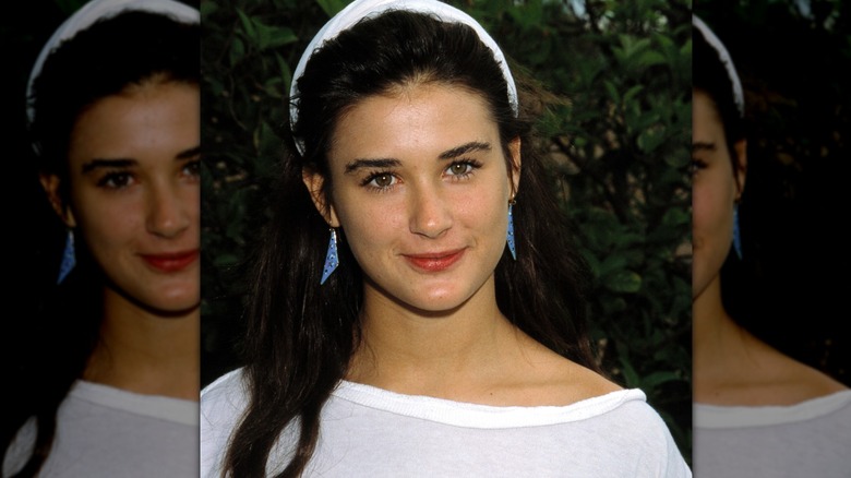 Young Demi Moore with white headband and blue earrings