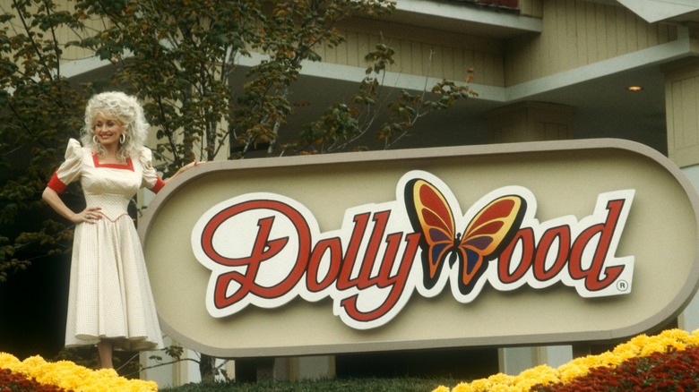 Dolly Parton posing with Dollywood sign