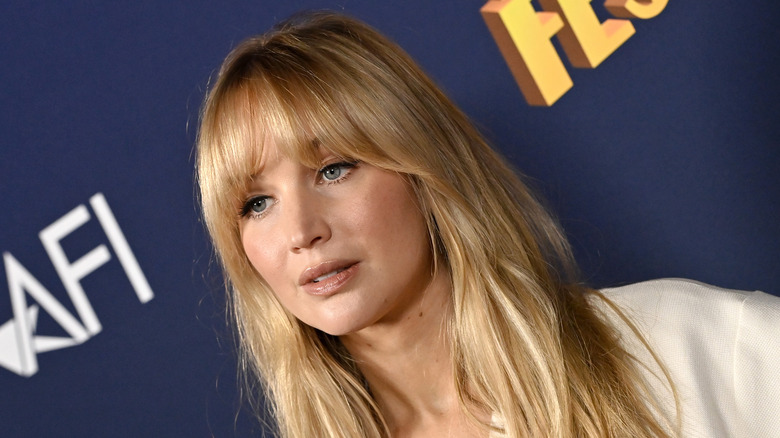 Jennifer Lawrence posing with bangs in front of media wall.