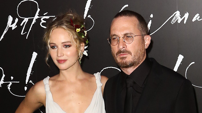 Jennifer Lawrence and Darren Aronofsky posing in front of media wall.