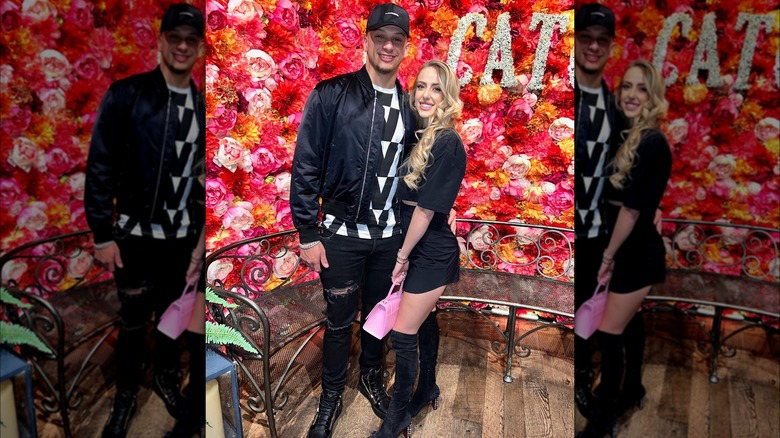 Patrick and Brittany Mahomes posing in front of a flower wall