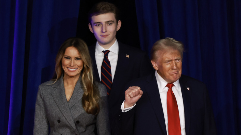 Melania and Barron Trump smiling while Donald Trump pumps fist