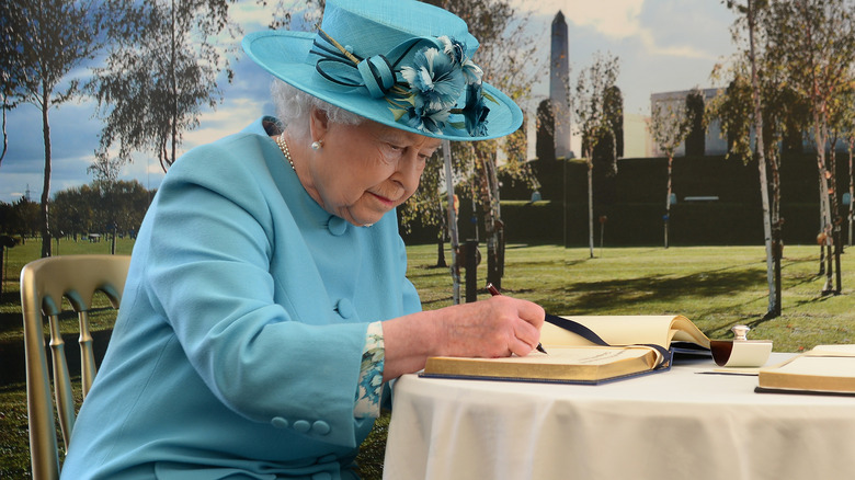 Queen Elizabeth writing in a book