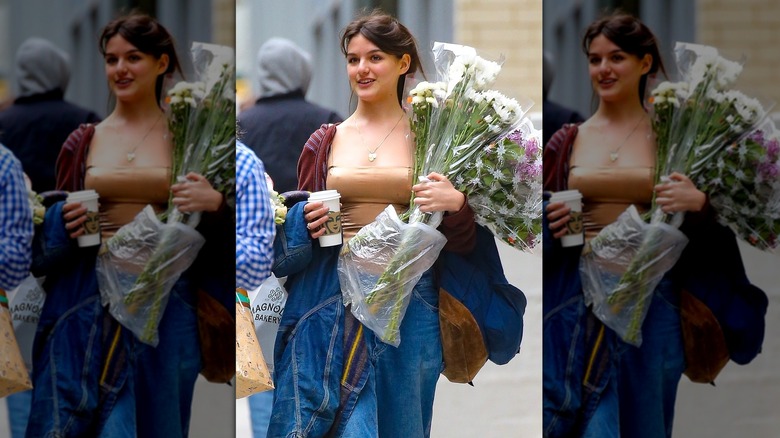 Suri Cruise walking outside holding flowers