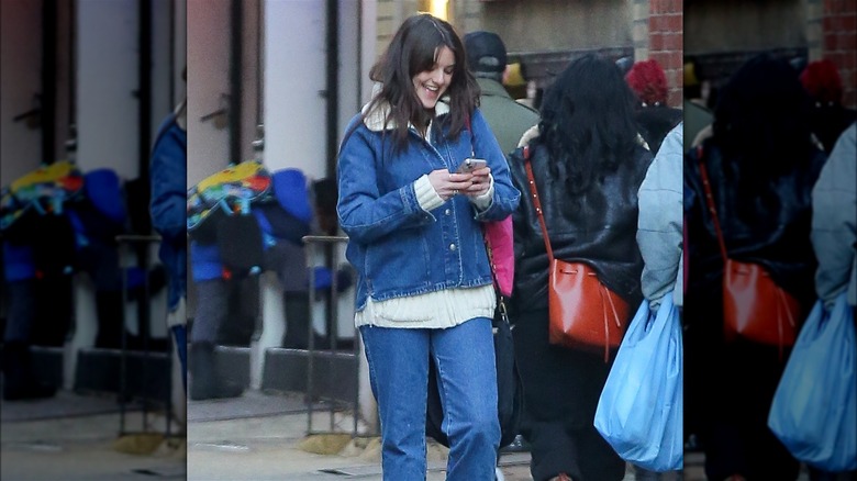 Suri Cruise walking, looking at phone, smiling