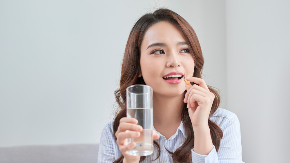 Smiling woman taking pill