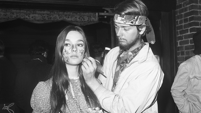 Man painting woman's face in 1970s