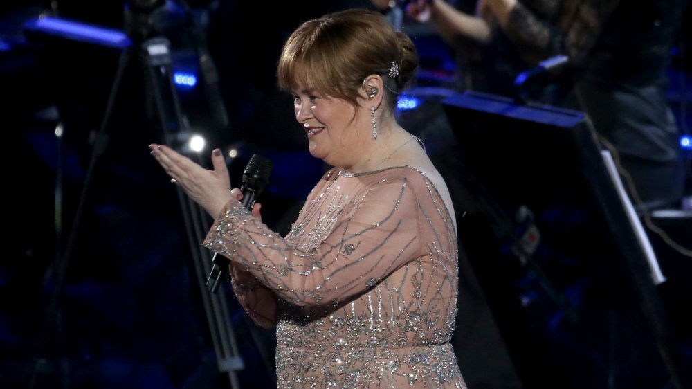 Susan Boyle smiling and gesturing while on stage