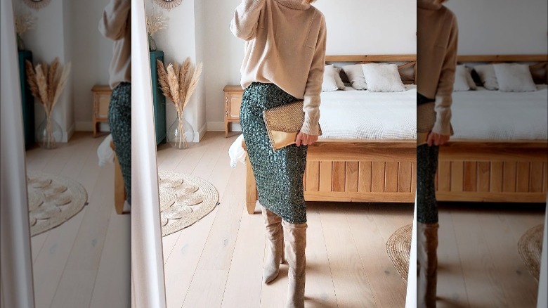 Person taking mirror selfie in bedroom wearing sparkly skirt and sweater