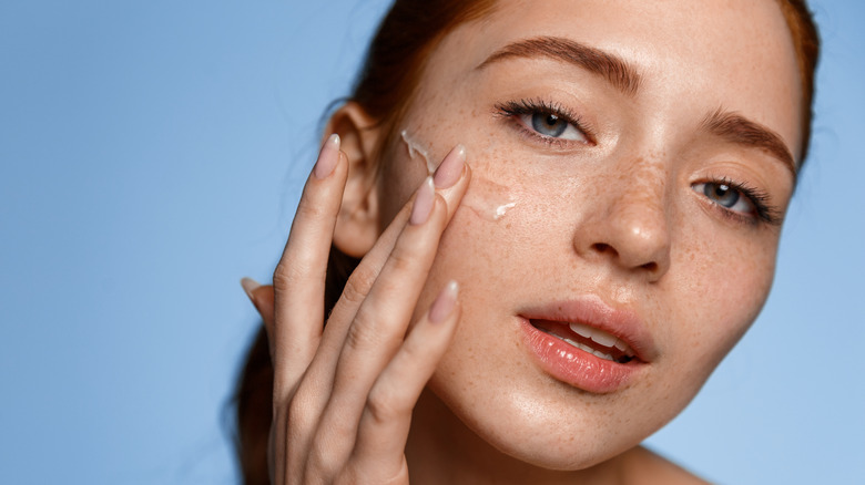 A woman applying moisturizer 