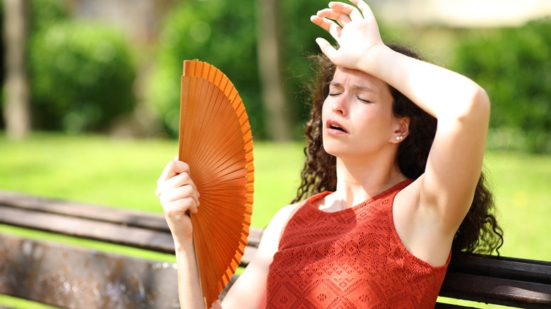 Sweaty woman using a fan