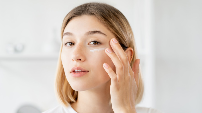 Woman applies under eye cream