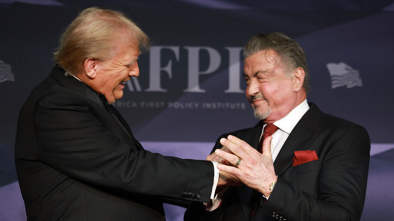 Donald Trump and Sylvester Stallone clasping hands and smiling