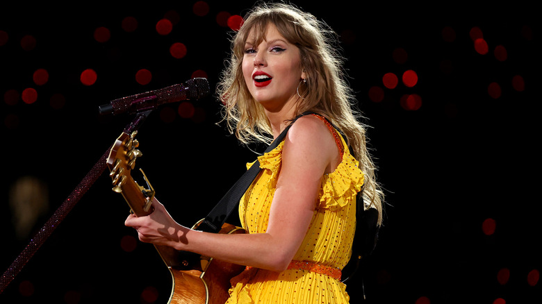 Taylor Swift playing guitar, looking over shoulder