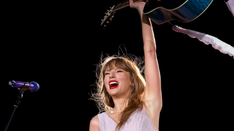 Taylor Swift holding guitar over head