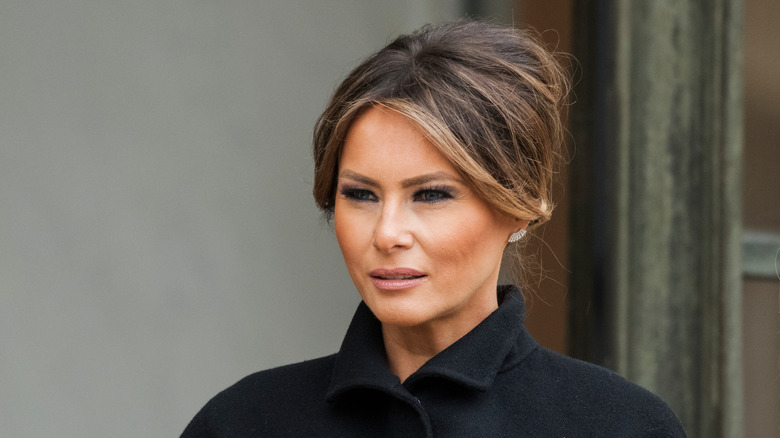 Melania Trump looking stern with an updo and dark coat