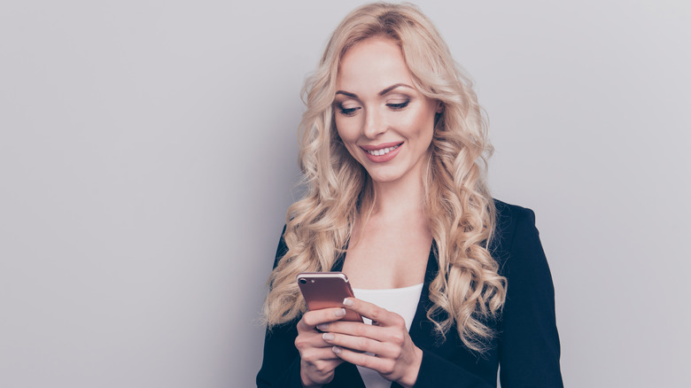 woman texting on phone against gray background