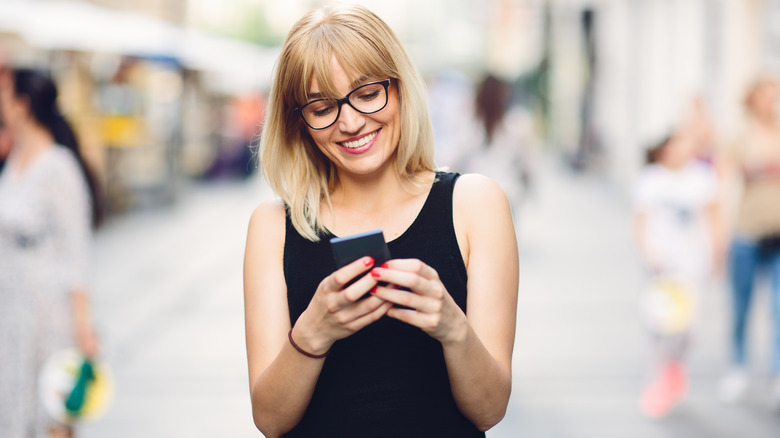 woman smiling at phone while texting