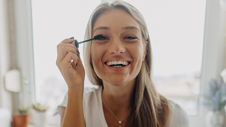 smiling woman putting on mascara