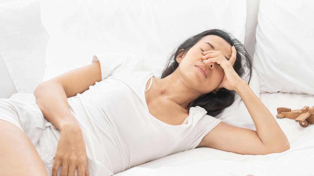 An exhausted woman covering her eyes in bed 