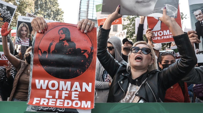 woman holding protest sign reading "for women, for life, for freedom"