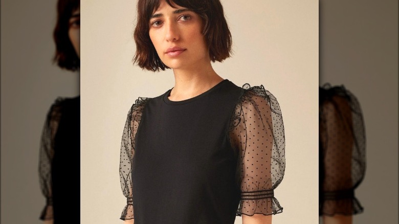 Model wearing black t-shirt with sheer sleeves