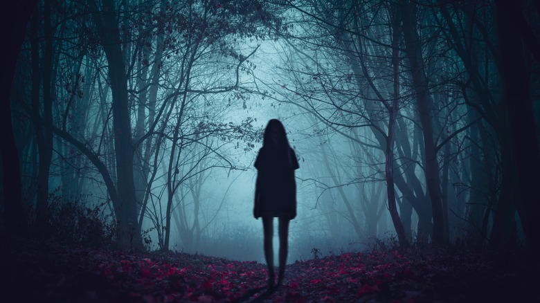 girl standing in scary forest 