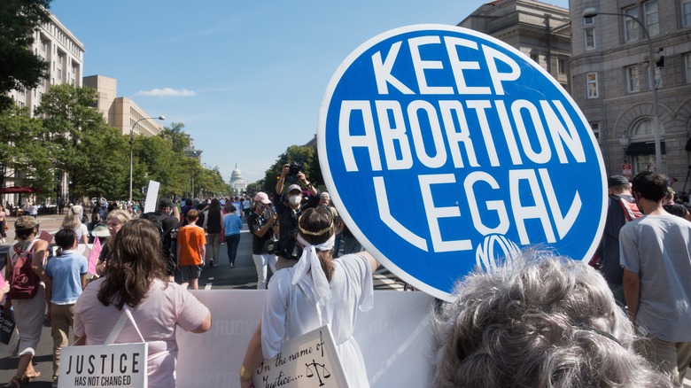 pro abortion protestors holding up signs walking through a crowded street