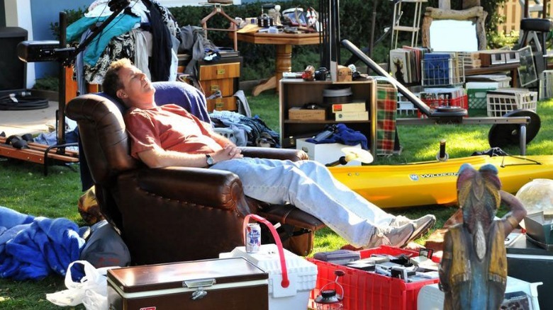 Man sleeping in chair on cluttered lawn