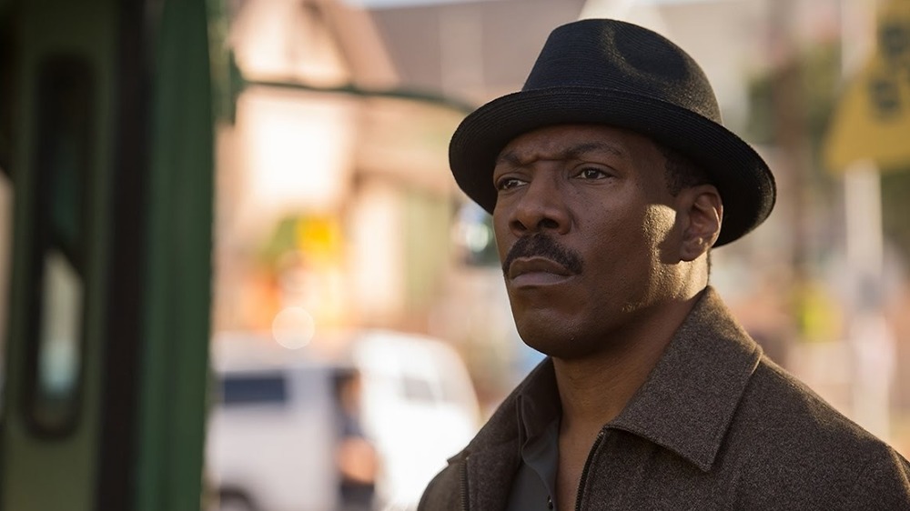 Eddie Murphy in fedora furrowing brow