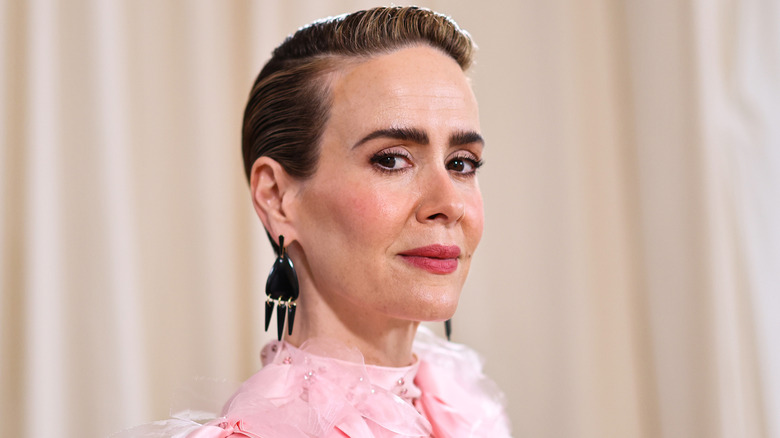 Closeup of Sarah Paulson in pink dress with slicked back hair