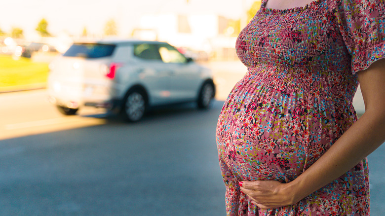 Pregnant belly with car in background