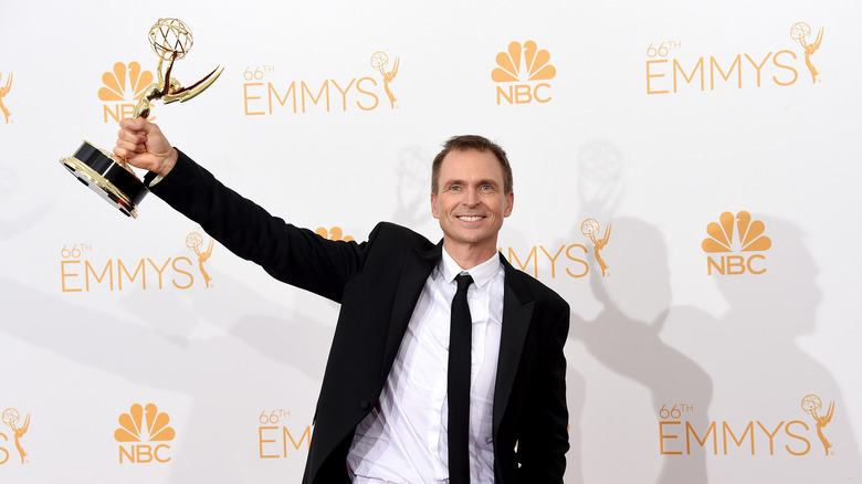 Amazing Race host Phil Keoghan holds up his Emmy