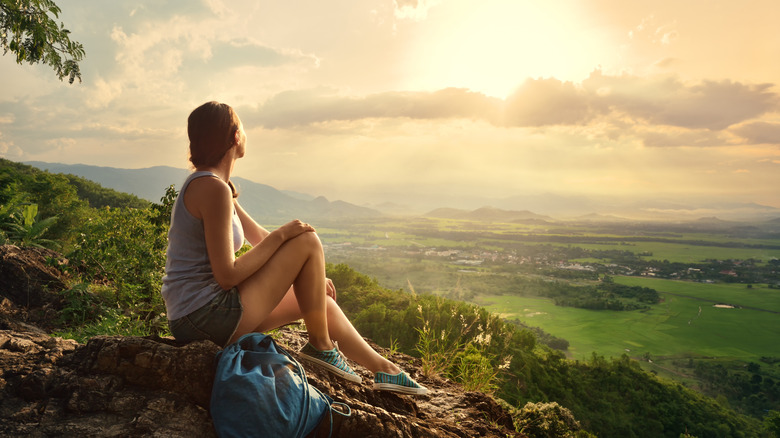 A woman sitting on a mountain top 