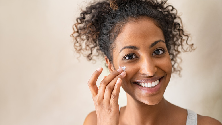 smiling woman applying facial cream