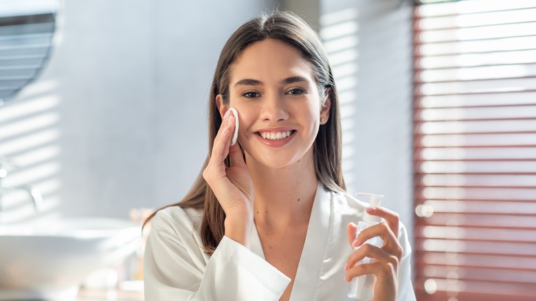 Woman applying toner to skin