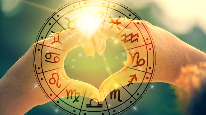 Hands forming a heart behind the zodiac wheel 