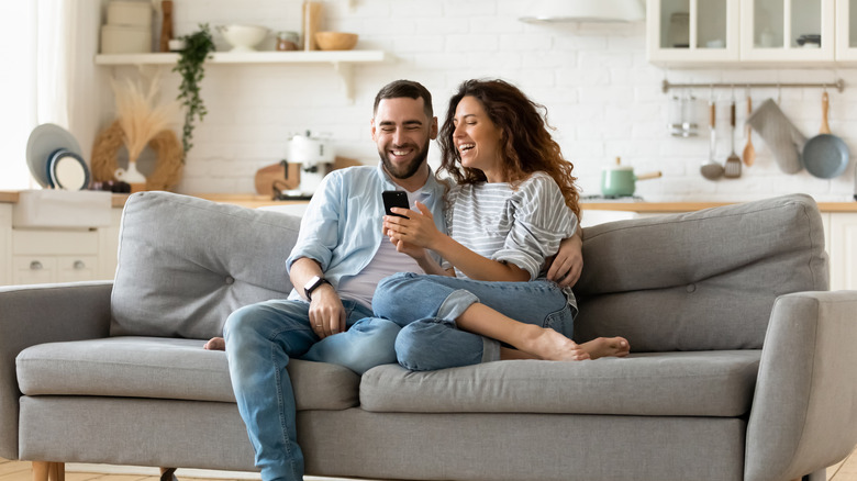 A man and woman laughing together on a couch 