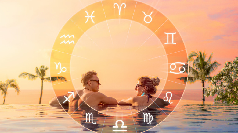 A man and woman in an infinity pool behind zodiac wheel 