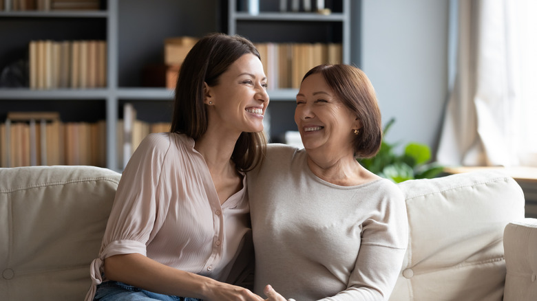 Two women embracing and smiling on a couch 