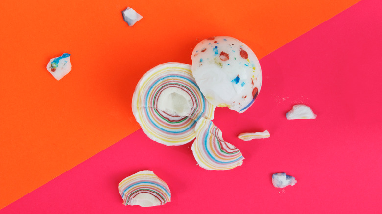 A shattered jawbreaker against a pink and orange background