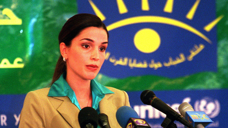 Queen Rania standing behind microphones at an event