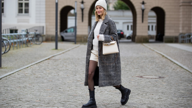 Woman wears tights with a gray coat and black boots