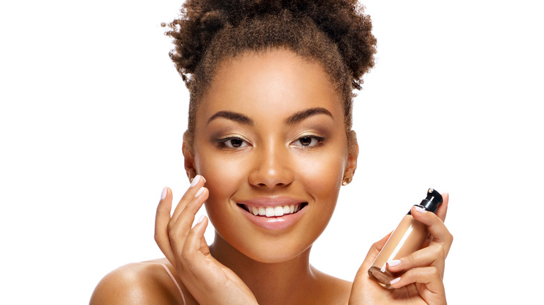 Woman applying concealer to face