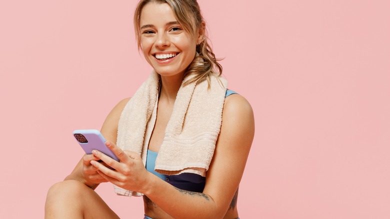 Woman wearing workout clothes holds phone