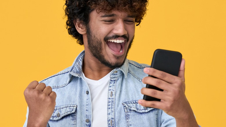 Man cheering while looking at phone