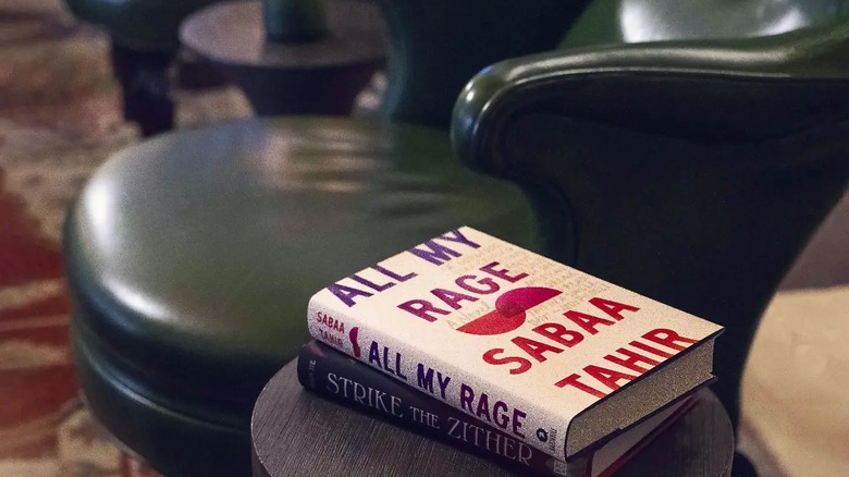 books stacked on a small table next to a leather chair